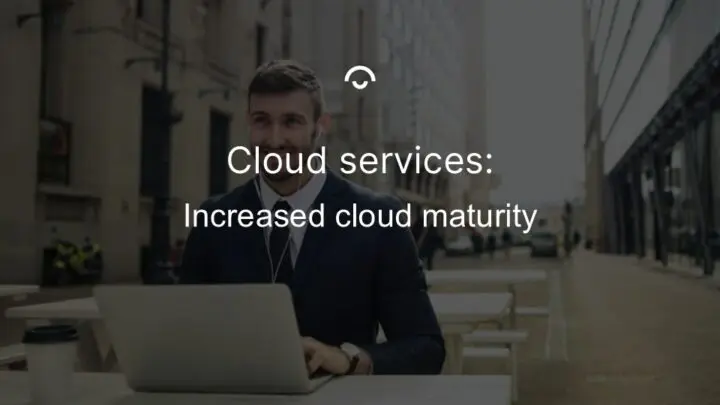 Article image: A happy person looks up from their laptop at an outdoor café with earphones in their ears. Text: Increased cloud maturity