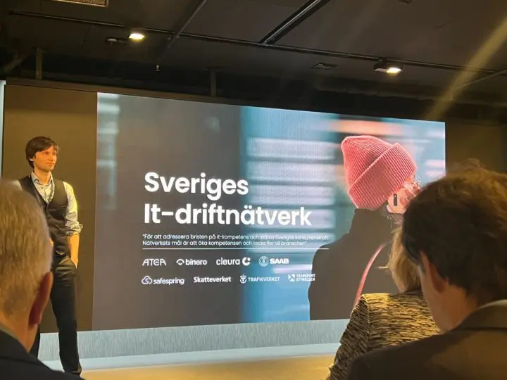 People look at a screen with the message ‘Sweden's IT operating network’. Människor tittar på en skärm med budskapet ”Sveriges It-driftnätverk”.