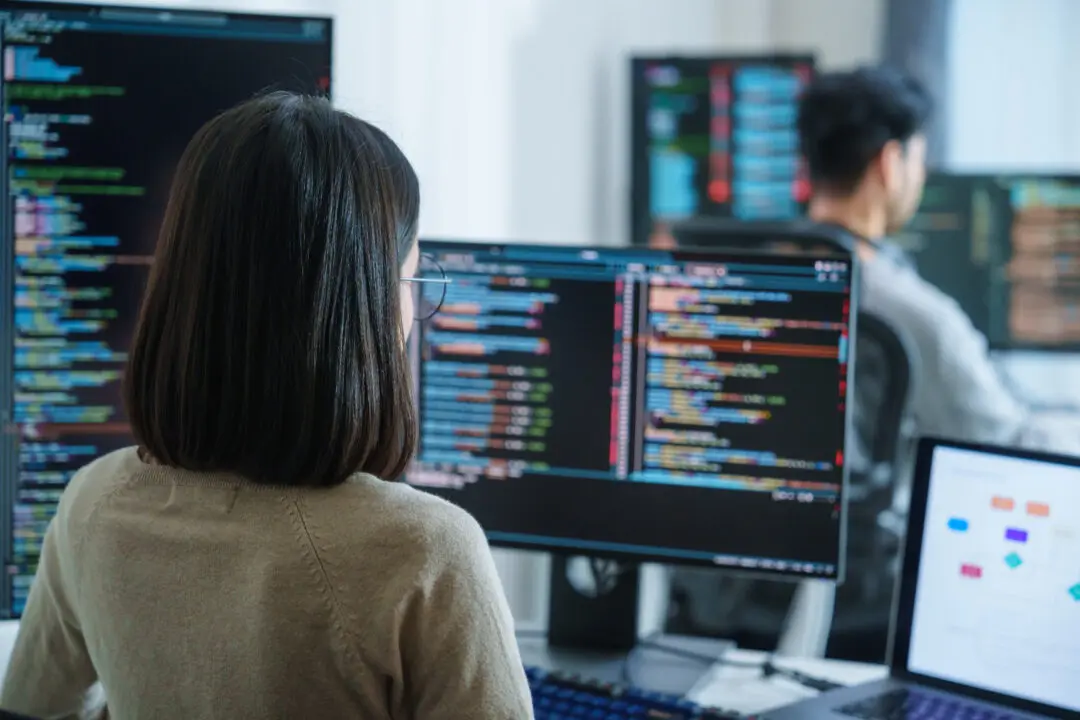 Software developers working on multiple screens displaying code and application diagrams in a modern office