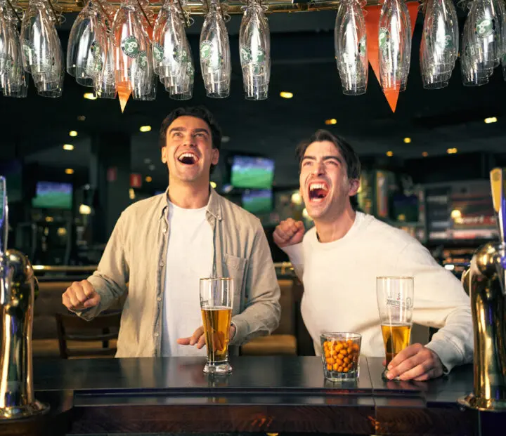 Two people cheering in a bar