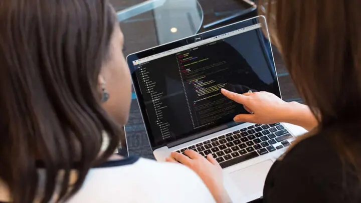 Two people are discussing code on a screen.
