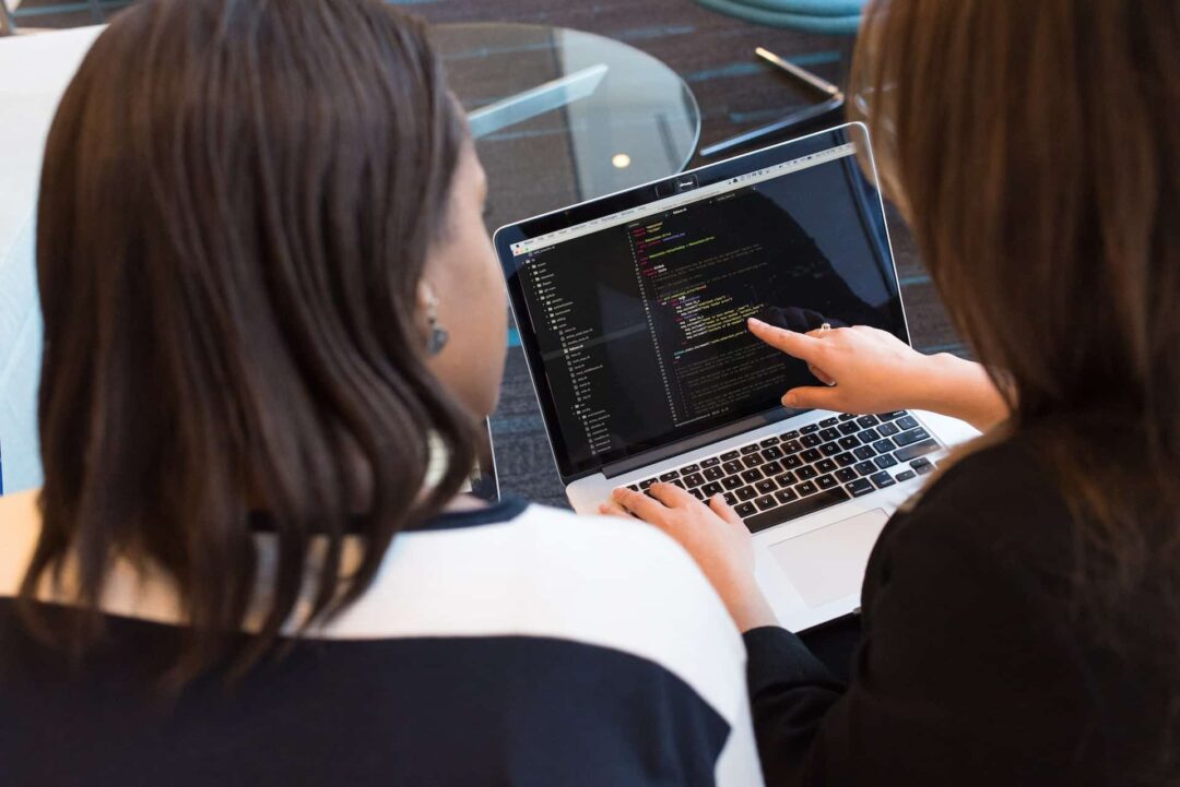 Colleagues working with code at a computer.