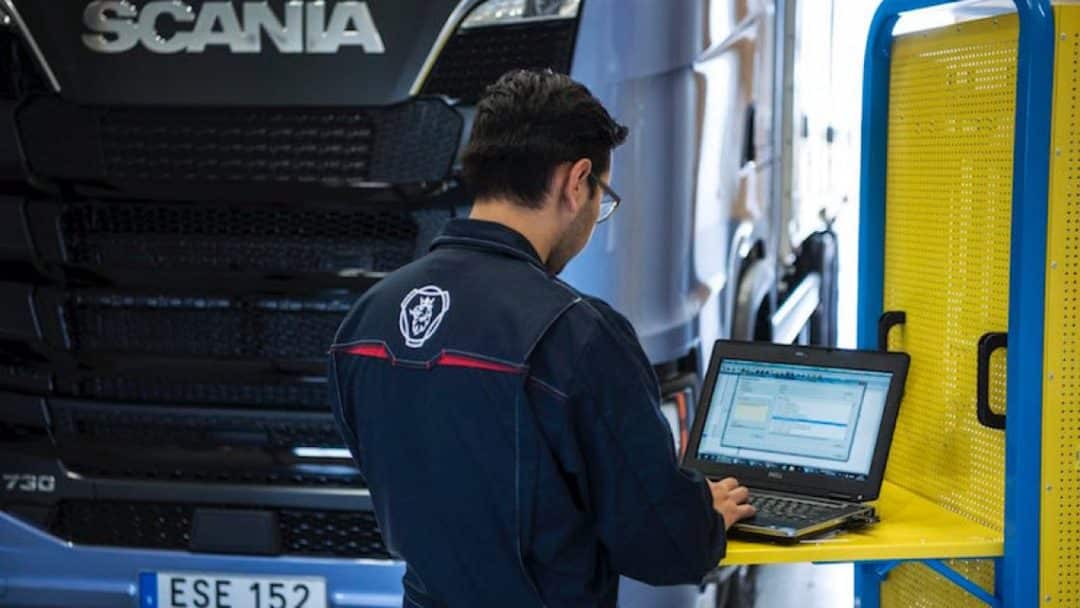Working on a computer in front of a Scania lorry.