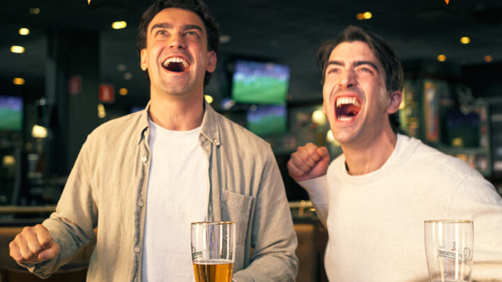 Two excited people are watching TV and shouting with joy