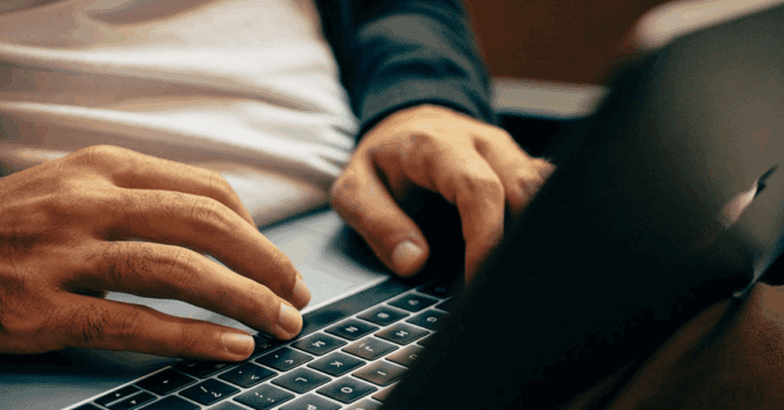 Hands typing on a laptop