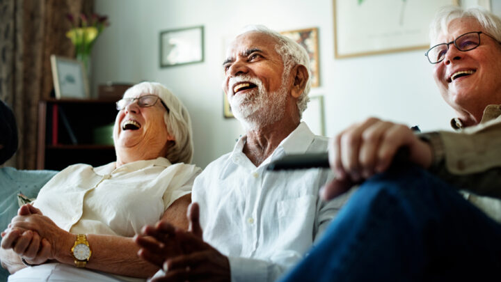 Happy elderly people watching TV together