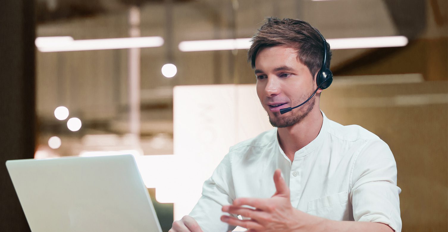 Support technician talking in headset at laptop.
