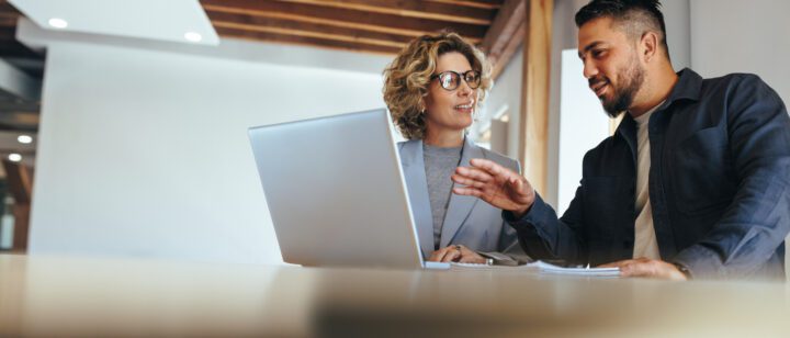 To kolleger diskuterer på en bærbar computer.