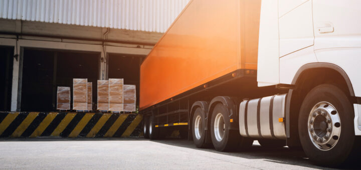 A truck has reversed into a loading bay where there are pallets with boxes