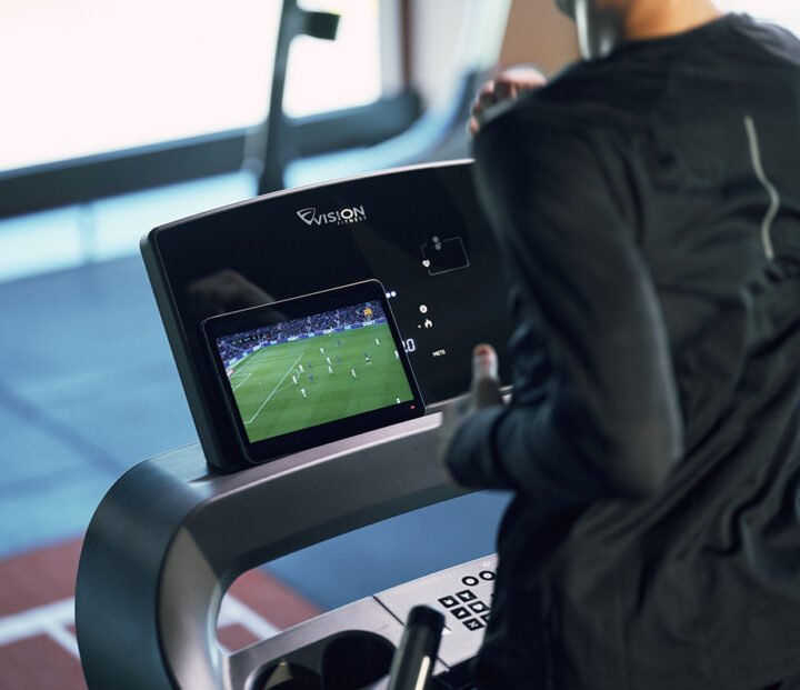Person running on treadmill watching football