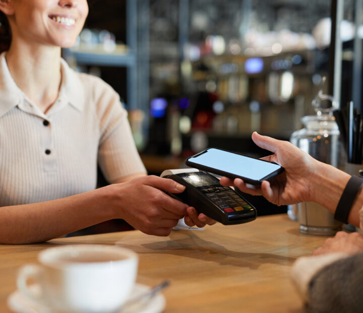 Person pays with their smartphone to a card reader at a café