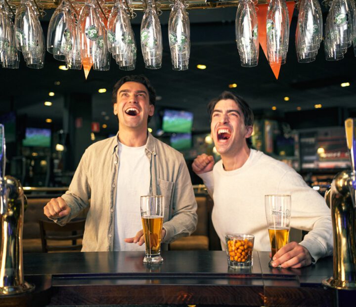 Two people cheering in a bar
