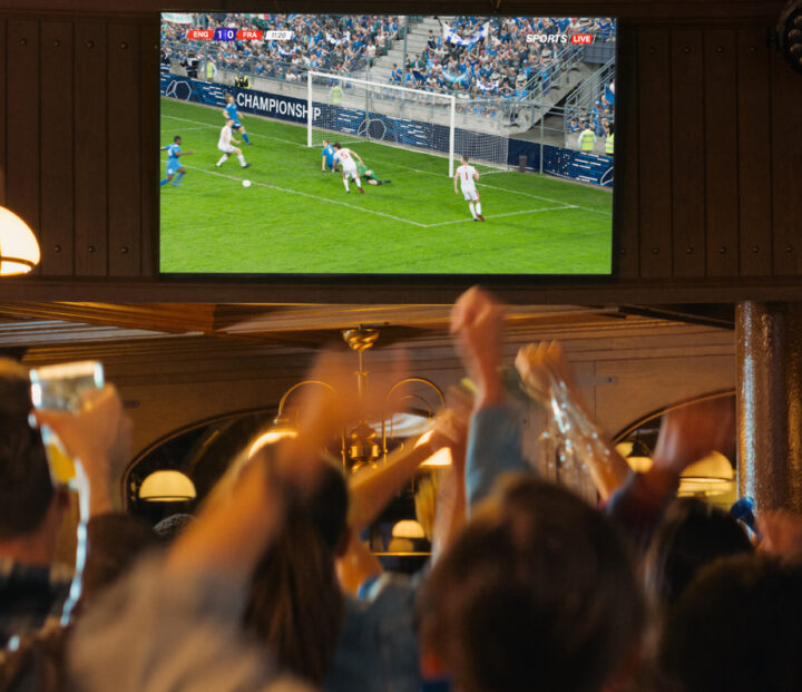 People in a bar watching football on TV and cheering