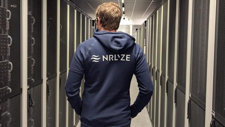 Person wearing a hoodie with the Nrlyze logo on the back walks into Bineros' server room.