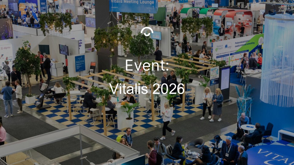 Stor messehal med mennesker, stande og skilte. Teksten "Event: Vitalis 2026" er i midten af billedet.