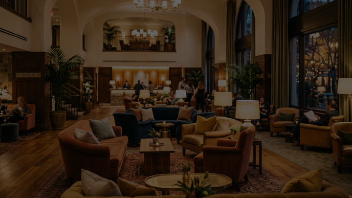 Ljus och elegant hotellobby med soffgrupper, stora fönster, växter och gäster som sitter och samtalar.